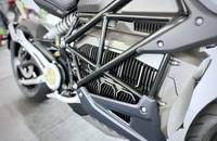 Seitliche Ansicht eines silbernen E-Motorrads mit sichtbarem Rahmen und Akkugehäuse.
