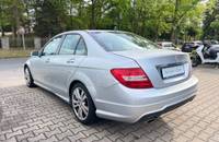 Silberner Mercedes-Benz C-Klasse von hinten links auf einem gepflasterten Gelände.