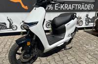 Seitenansicht eines weißen E-Scooters (ZERO) auf Pflastersteinen vor einem Banner.