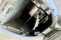 Nahaufnahme eines geöffneten Fahrzeugkompartiments mit sichtbaren elektrischen Anschlüssen und Verriegelungen.