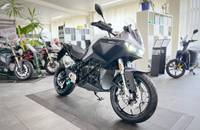 Eine silberne Elektro-Motorrad ist in einem Showroom auf einem grauen Boden ausgestellt.