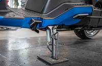 Detailaufnahme des Unterbaus eines blauen Elektrofahrzeugs mit sichtbarem Ständer.