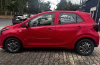 Seitenansicht eines roten KIA Picanto auf einem gepflasterten Platz.