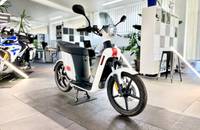 Ein weißer Elektroroller (ANDERE eS3 EVO) wird in einem hellen Showroom aufgestellt.