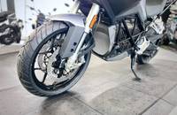 Seitenansicht eines silbernen E-Motorrads auf einem Verkaufsboden. Das Vorderrad und der Aufbau sind zu sehen.