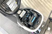 Nahaufnahme des geöffneten Kofferraums, die die sichtbaren elektrischen Komponenten und Kabel des Elektrofahrzeugs zeigt