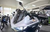 Nahaufnahme der silbernen Front eines E-Motorrads (ZERO) mit Windschutzscheibe in einem Showroom.