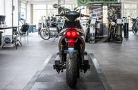 Heckansicht eines grauen E-Motorrads in einem Showroom.