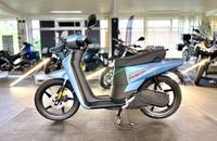 Seitenansicht eines hellblauen Elektro-Scooters in einem Autohaus.
