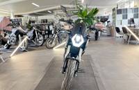 Schwarzes Motorrad in einem hellen Showroom, das im Zentrum platziert ist.