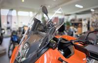 Nahaufnahme der orangefarbenen Front eines Elektrorollers mit Windschutzscheibe und Lenker.