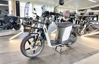 Seitenansicht eines weißen, modernen E-Scooters (ANDERE eSPro) in einem gut beleuchteten Showroom.