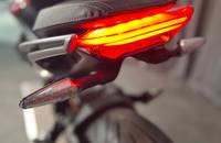 Heckansicht eines Motorrads mit leuchtendem Rücklicht und Blinker.