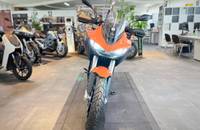 Frontalansicht eines orangefarbenen E-Motorrads in einem Showroom.