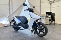 Weißer Elektroroller (RAY 7.7) in Seitenansicht in einem Showroom.