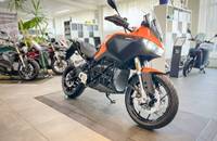 Eine orangefarbene Motorrad-ADV-Maschine steht in einem Showroom.