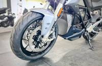 Seitenansicht eines silbernen E-Motorrads mit Fokus auf dem Vorderrad und der Bremsanlage.