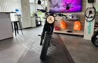 Frontalansicht eines schwarzen Motorrads in einem Autohaus-Showroom.
