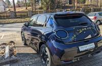 Dunkelblaues Nissan Micra EV im Dreiviertel-Heckwinkel auf einem Autohausparkplatz.