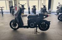 Seitenansicht eines grauen elektrischen Scooters in einem Showroom.
