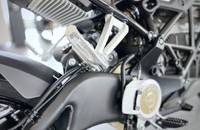 Nahaufnahme der vorderen mechanischen Komponenten eines E-Motorrads, sichtbar sind die Gabel und die Bedienelemente.